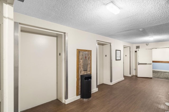 hallway featuring dark hardwood / wood-style flooring, a textured ceiling, and elevator