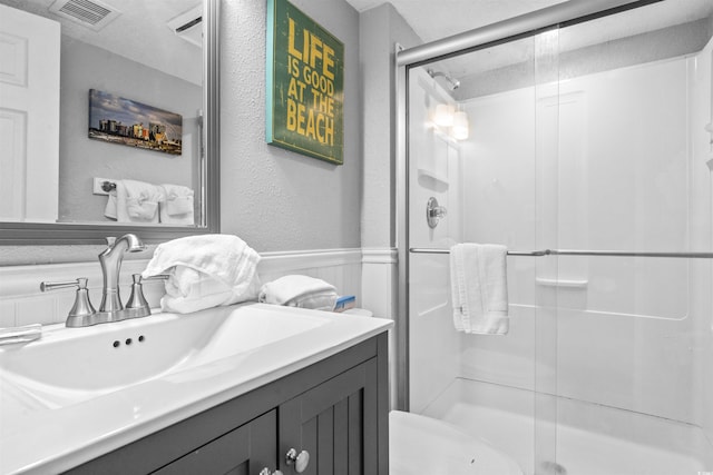 bathroom featuring a shower with door and vanity