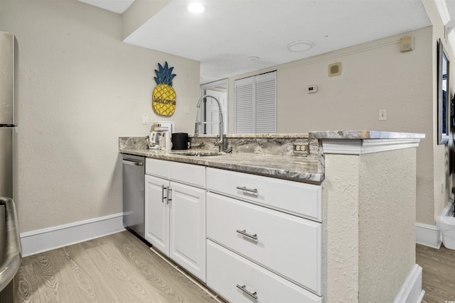 kitchen with sink, stainless steel dishwasher, white cabinetry, and light wood-type flooring