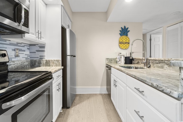 kitchen with stainless steel appliances, white cabinets, decorative backsplash, and sink