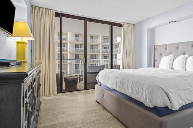 bedroom with a wall of windows, access to exterior, and light hardwood / wood-style flooring