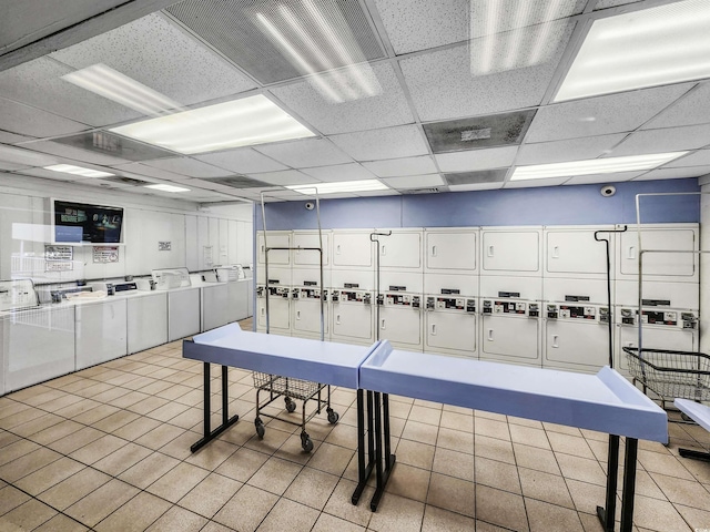 recreation room featuring separate washer and dryer, a paneled ceiling, and stacked washer / dryer