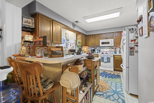 kitchen with kitchen peninsula, a kitchen bar, a textured ceiling, white appliances, and crown molding