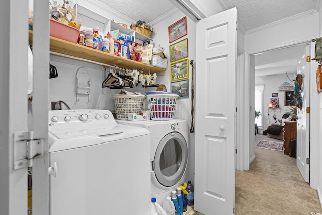 clothes washing area with light carpet, a textured ceiling, washing machine and dryer, and crown molding