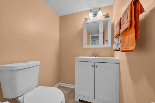 bathroom with hardwood / wood-style flooring, vanity, toilet, and a textured ceiling