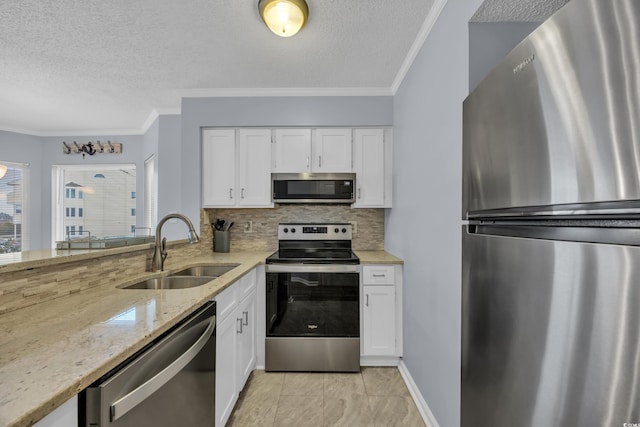 kitchen featuring sink, light stone countertops, tasteful backsplash, white cabinetry, and stainless steel appliances