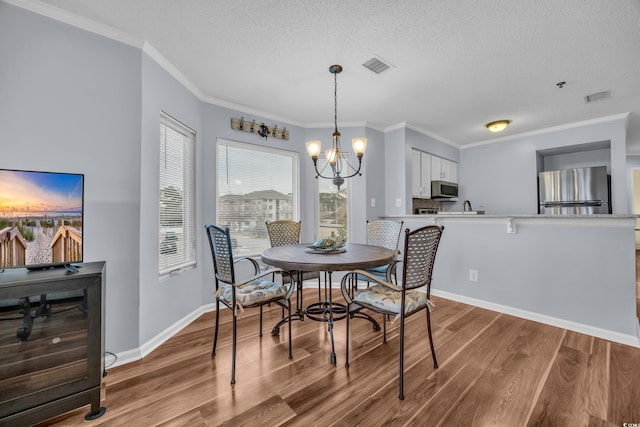 dining space featuring light hardwood / wood-style flooring, ornamental molding, and a notable chandelier