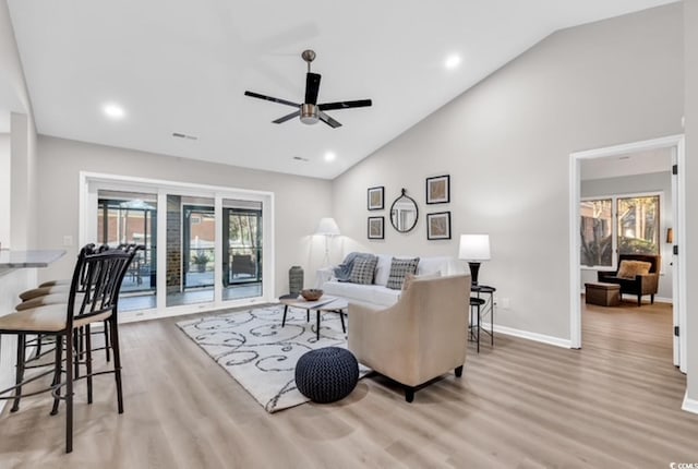 living room with ceiling fan, plenty of natural light, high vaulted ceiling, and light hardwood / wood-style floors