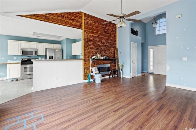 unfurnished living room featuring light hardwood / wood-style flooring, high vaulted ceiling, ceiling fan, and a large fireplace