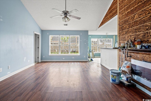 unfurnished living room with ceiling fan with notable chandelier, hardwood / wood-style floors, and vaulted ceiling