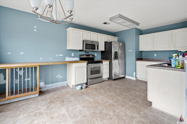 kitchen featuring decorative light fixtures, white cabinets, light tile patterned floors, and stainless steel appliances