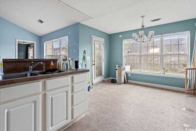 kitchen featuring pendant lighting, sink, white cabinetry, and a textured ceiling