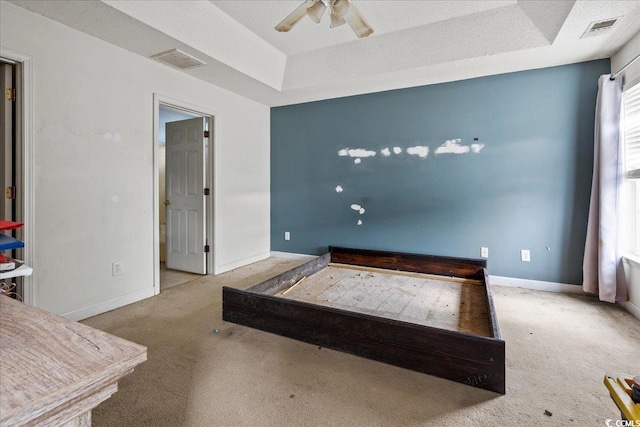 bedroom with ceiling fan, light carpet, and a raised ceiling