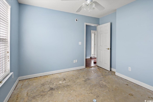 unfurnished room with ceiling fan and concrete flooring