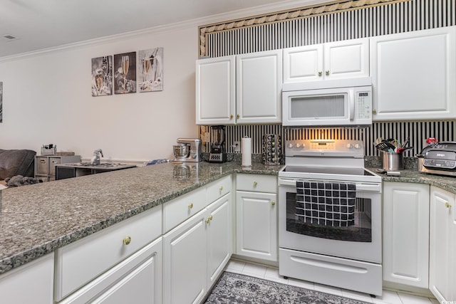 kitchen featuring white cabinets, dark stone counters, white appliances, light tile patterned floors, and ornamental molding