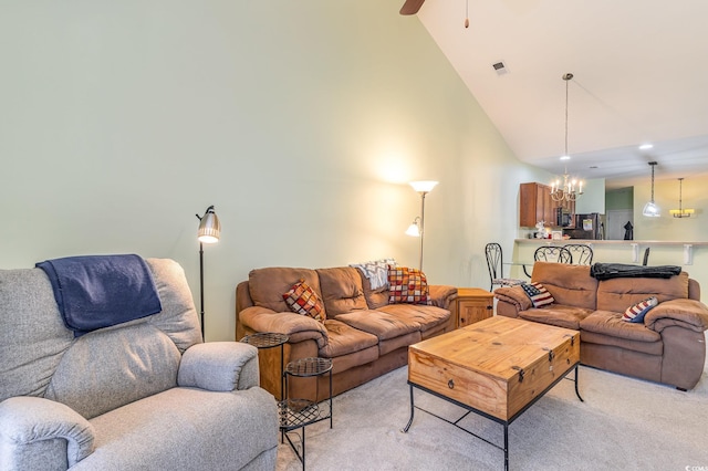 living area with light carpet, visible vents, ceiling fan with notable chandelier, and high vaulted ceiling