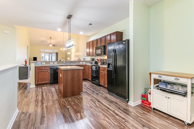 kitchen featuring visible vents, black appliances, a peninsula, dark wood-style flooring, and vaulted ceiling