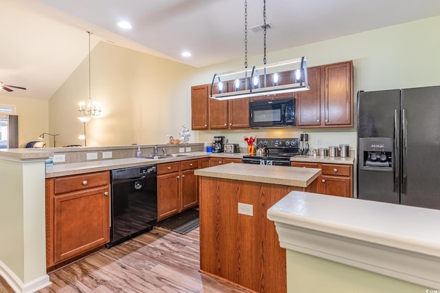 kitchen with black appliances, a sink, decorative light fixtures, a peninsula, and light countertops