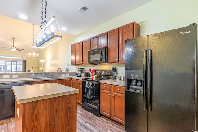 kitchen featuring visible vents, a sink, hanging light fixtures, black appliances, and light wood-type flooring