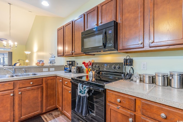 kitchen featuring black appliances, a sink, an inviting chandelier, light countertops, and lofted ceiling