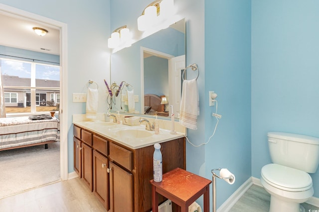 ensuite bathroom with ensuite bath, toilet, and a sink