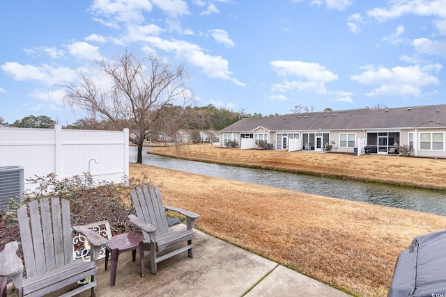 exterior space featuring a water view, central AC, and fence