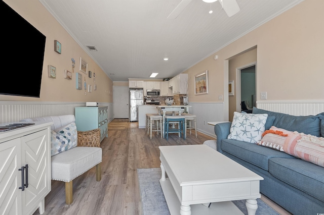 living room featuring crown molding, ceiling fan, and light wood-type flooring