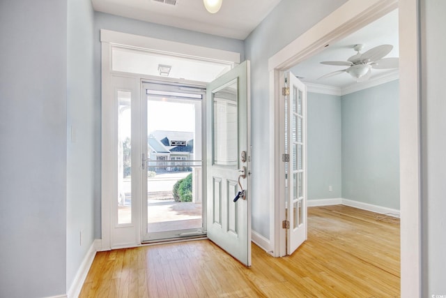 entrance foyer featuring crown molding, visible vents, a ceiling fan, wood finished floors, and baseboards