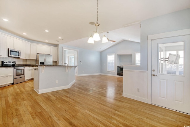 kitchen with a notable chandelier, dark countertops, appliances with stainless steel finishes, white cabinetry, and light wood-type flooring