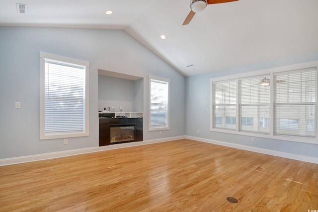 unfurnished living room with light wood-style floors, visible vents, vaulted ceiling, and a tiled fireplace