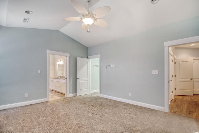 unfurnished bedroom with light carpet, baseboards, visible vents, and vaulted ceiling