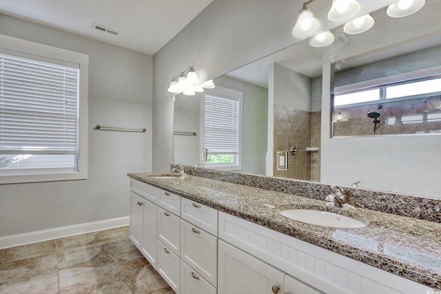 bathroom featuring baseboards, visible vents, a tile shower, and a sink