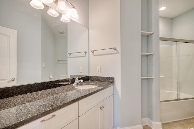 bathroom with built in shelves, bath / shower combo with glass door, an inviting chandelier, vanity, and tile patterned floors