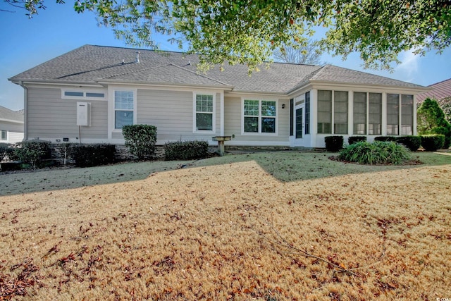 back of house featuring roof with shingles, a lawn, and a sunroom