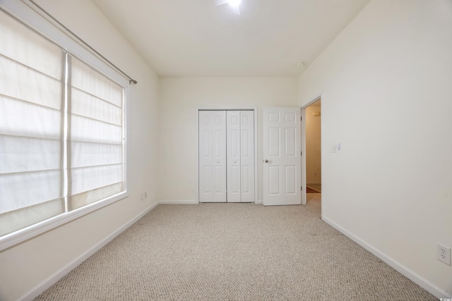 unfurnished bedroom featuring light colored carpet and a closet