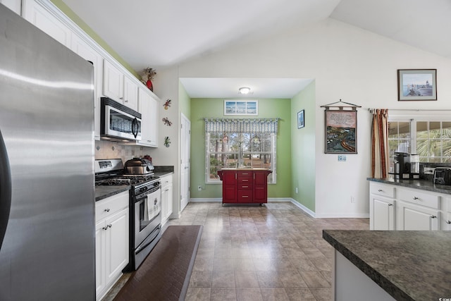 kitchen with white cabinets, appliances with stainless steel finishes, vaulted ceiling, and tasteful backsplash