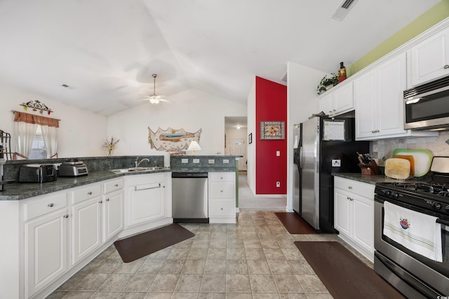 kitchen featuring appliances with stainless steel finishes, white cabinetry, lofted ceiling, and tasteful backsplash