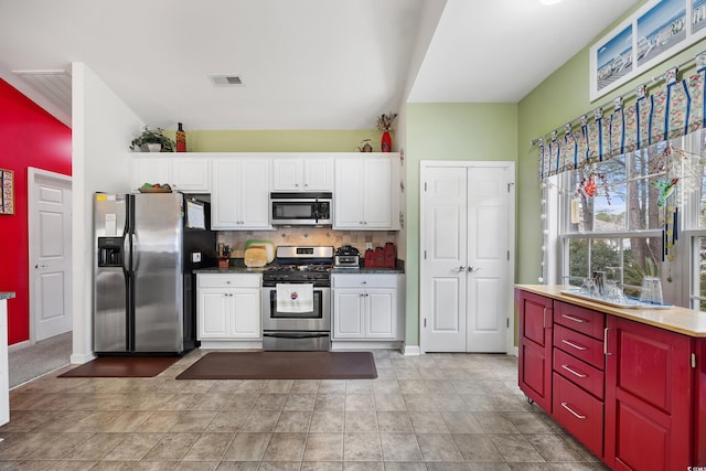 kitchen with appliances with stainless steel finishes, white cabinets, and backsplash