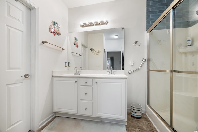 bathroom with a shower with door, vanity, and tile patterned floors