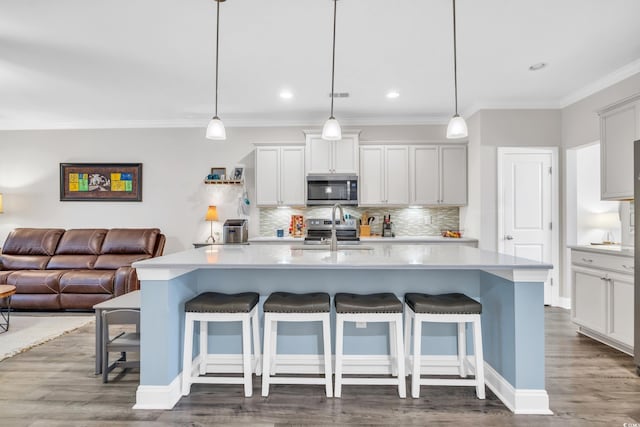 kitchen featuring an island with sink, appliances with stainless steel finishes, sink, and decorative light fixtures