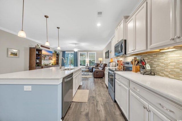 kitchen featuring pendant lighting, sink, appliances with stainless steel finishes, an island with sink, and white cabinets