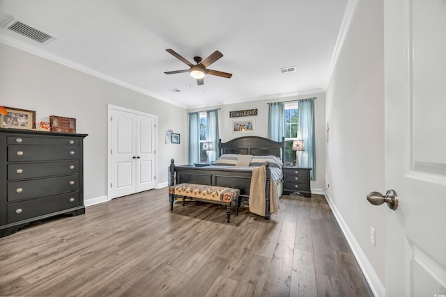 bedroom with wood finished floors, visible vents, ornamental molding, and baseboards