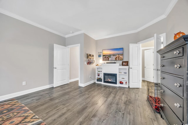 living area featuring baseboards, wood finished floors, crown molding, and a glass covered fireplace
