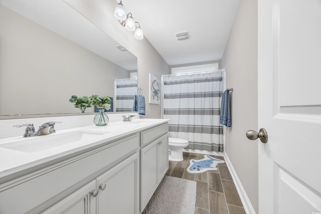 bathroom with walk in shower, vanity, and toilet