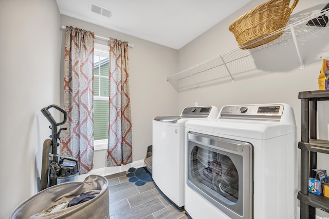 clothes washing area with laundry area, baseboards, visible vents, wood tiled floor, and washer and clothes dryer