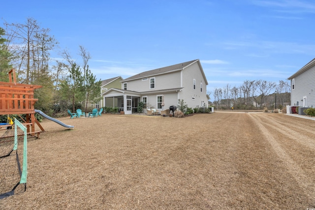 back of property with a playground and a sunroom