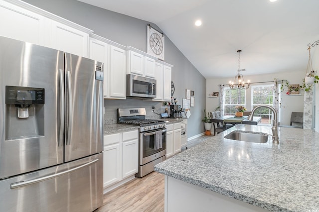 kitchen featuring lofted ceiling, sink, stainless steel appliances, light stone countertops, and white cabinets