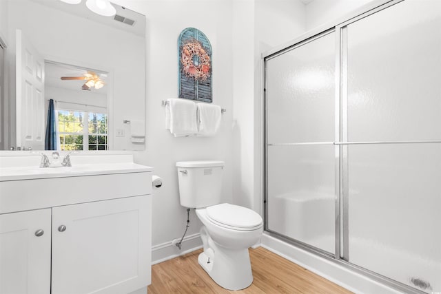 bathroom with ceiling fan, vanity, toilet, wood-type flooring, and a shower with shower door