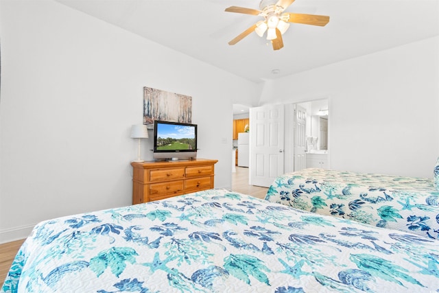 bedroom featuring ceiling fan, light hardwood / wood-style floors, ensuite bath, and white fridge