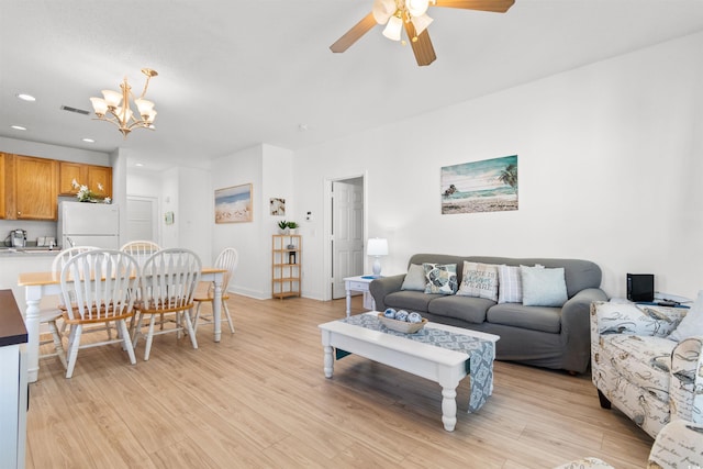 living room featuring ceiling fan with notable chandelier and light hardwood / wood-style flooring